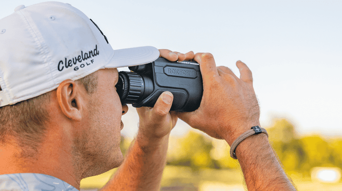 Man holding Rokform Rangefinder 18X in an open golf course fairway