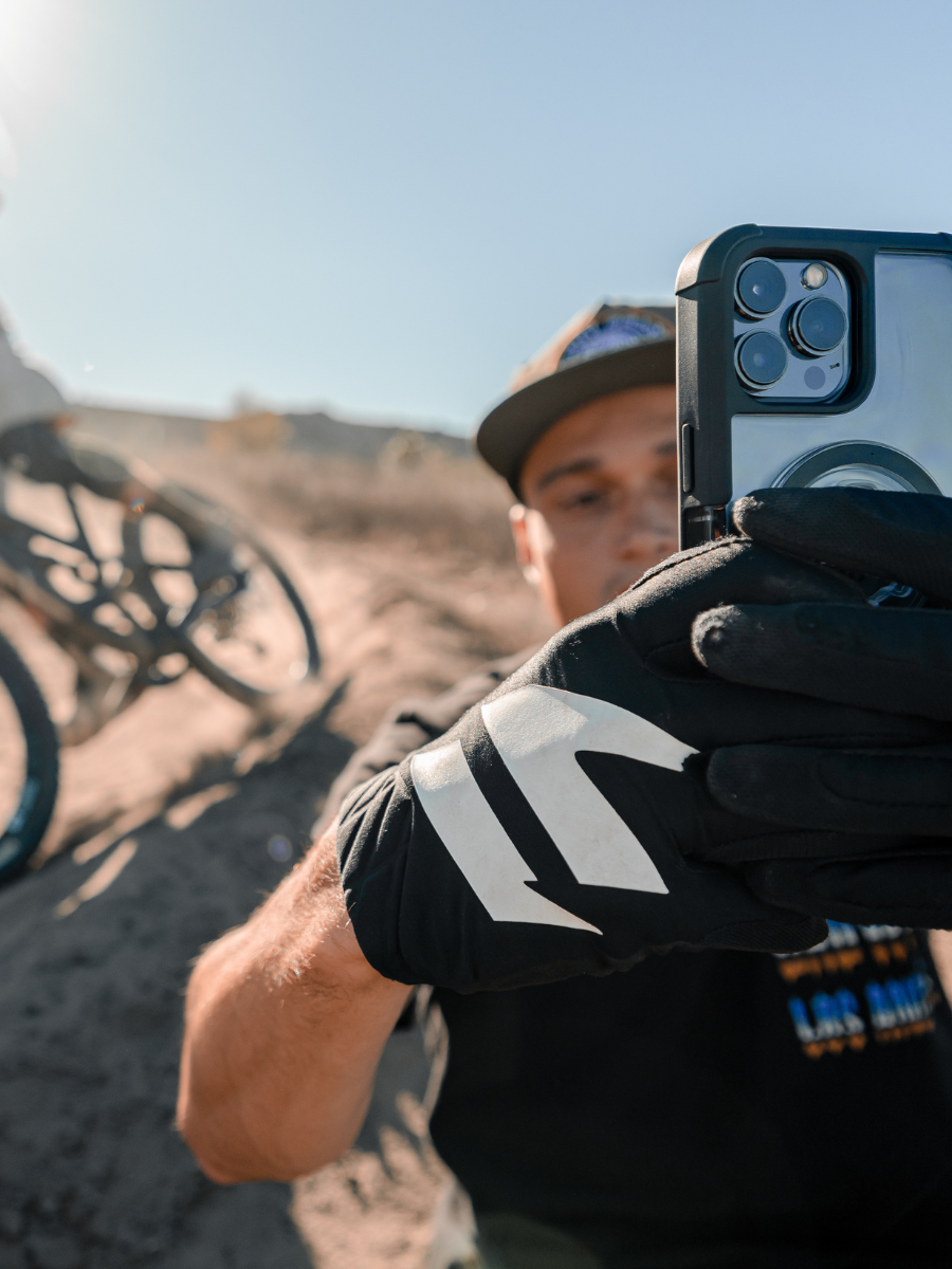 Mountain biker taking photo of rider behind him with a ROKFORM rugged iPhone case