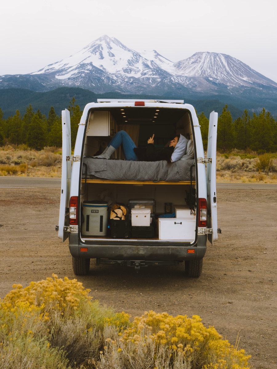 Sprinter van in front of mountains with trunk open full of gear