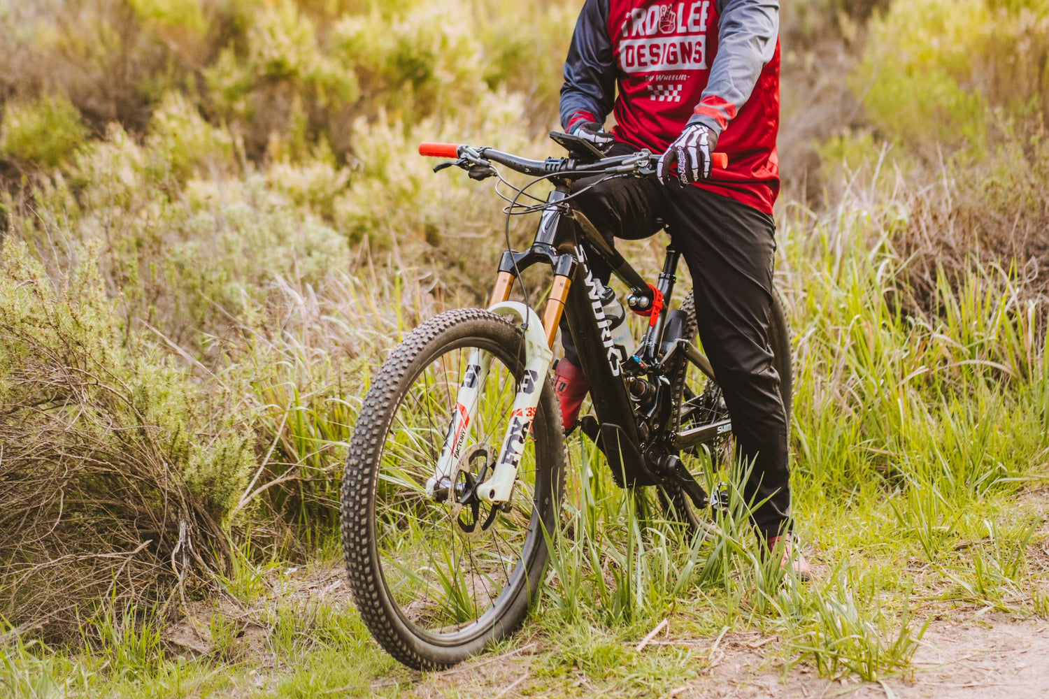 A mountain biker takes a break from riding to check his phone on his ROKFORM V4 Pro Series Bike Phone Mount.