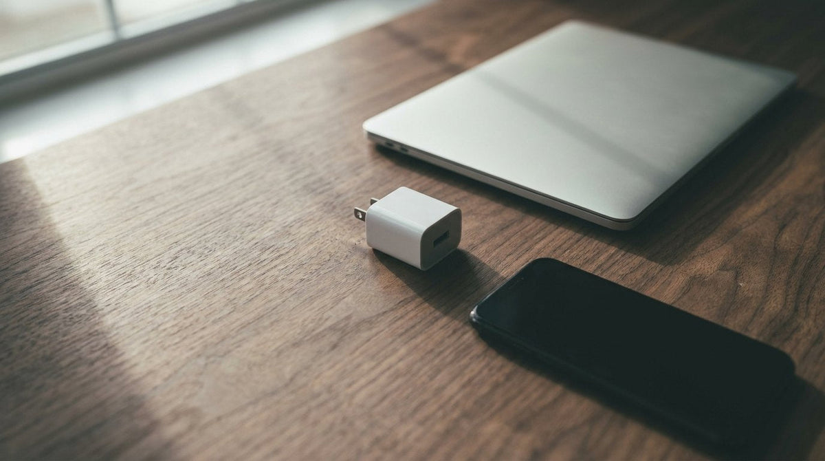 Compact charger beside a laptop and phone