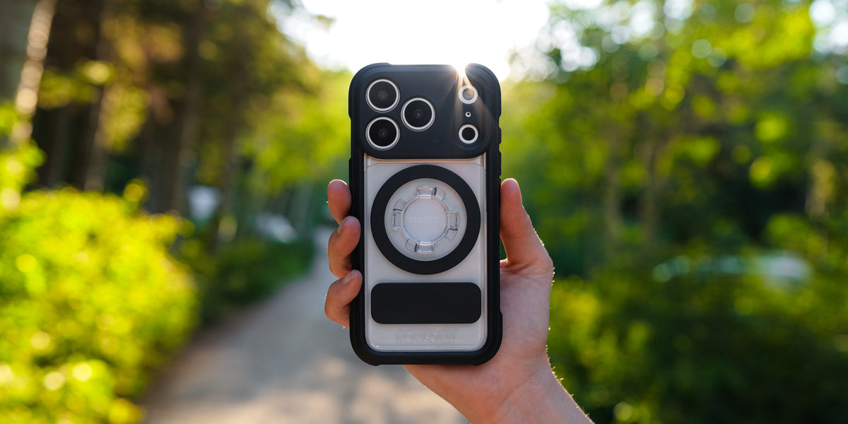 Rokform Crystal Case held in hand outdoors, clear back showing the phone underneath